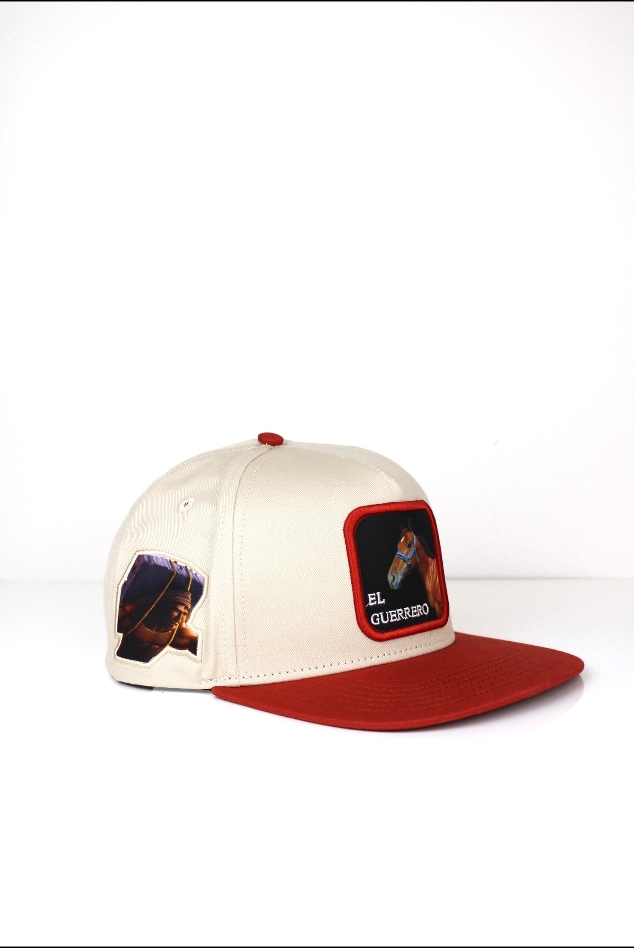 A beige and red baseball cap with 3D embroidered text and an image of el guerrero horse on the front.
