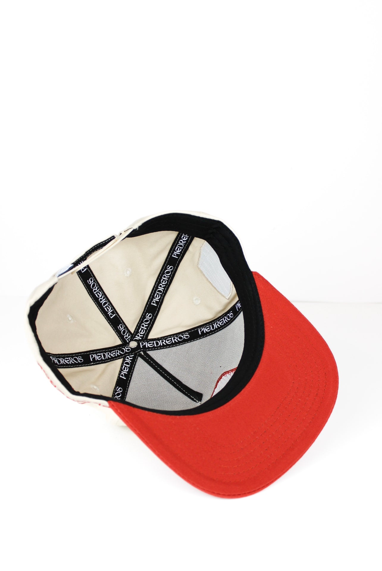 Inside of a beige and red baseball cap