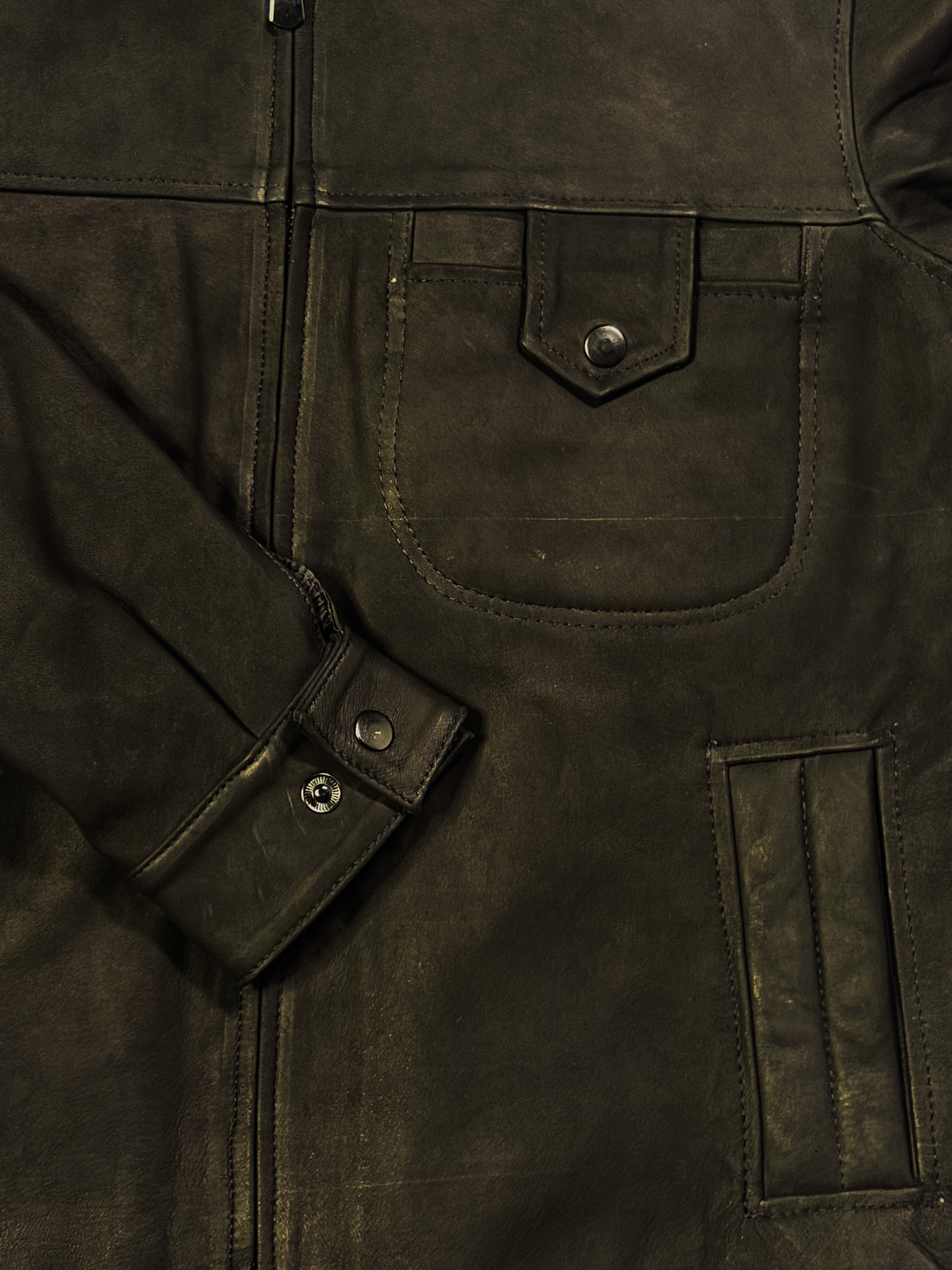 Close-up of a dark black leather jacket with button details