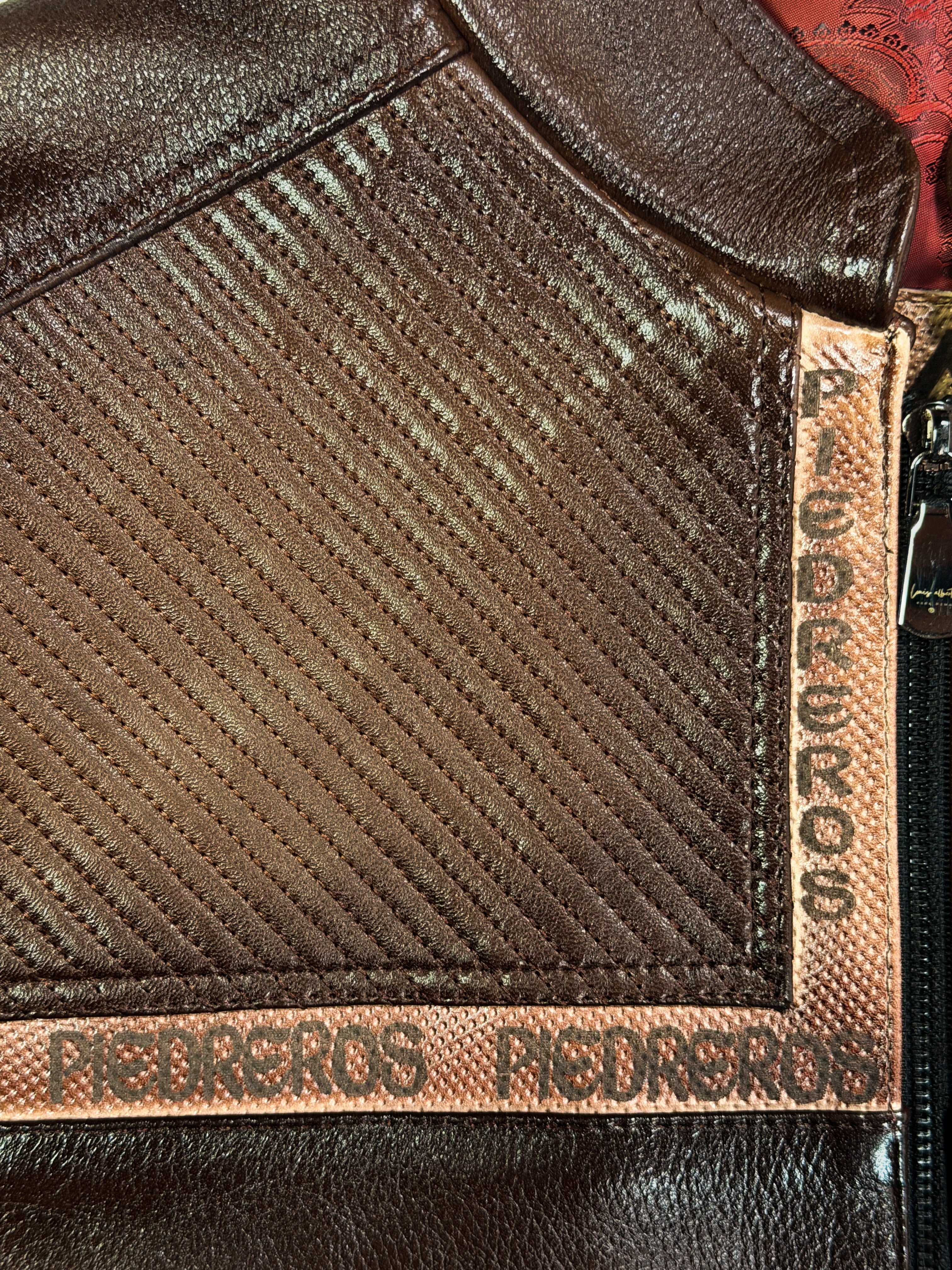 Close-up of a brown leather jacket with 'Pedreros' branding.
