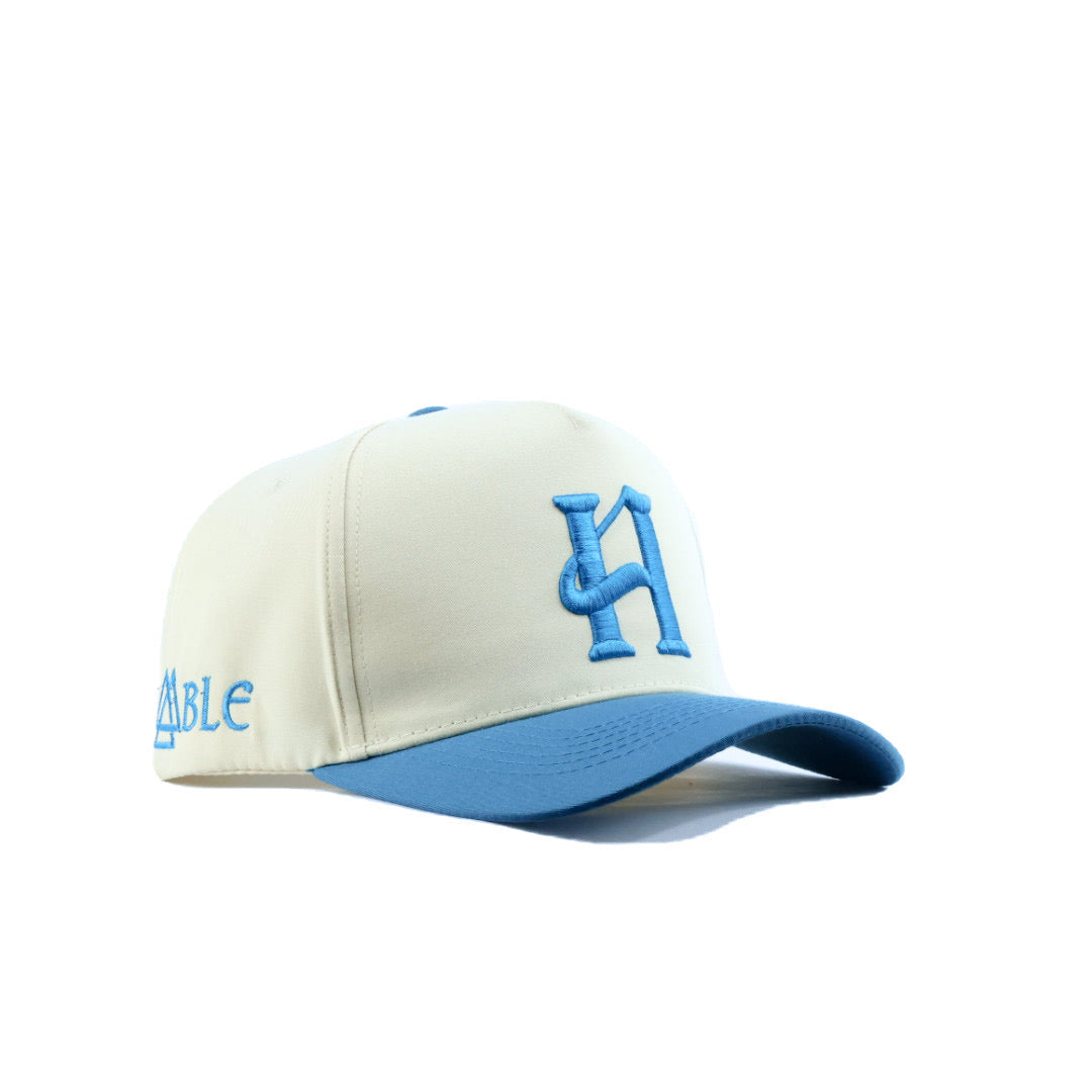cream and blue cap with branding on a white background
