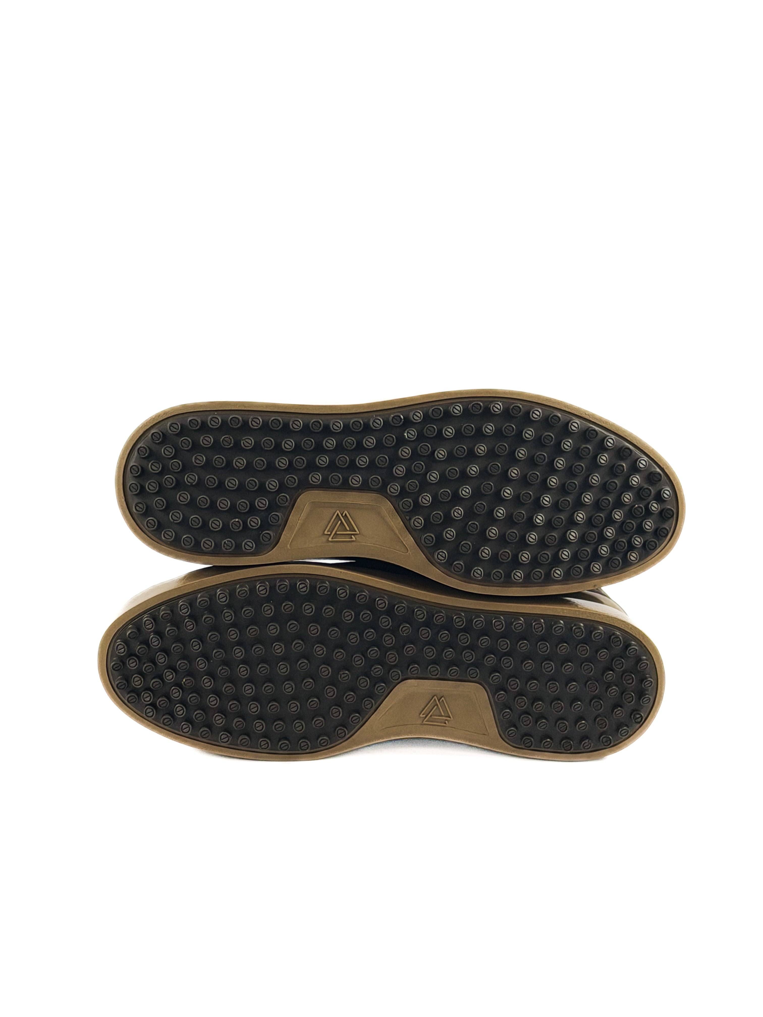 Bottom of a pair of brown bulls neck laced sneakers with tan soles and durable traction
