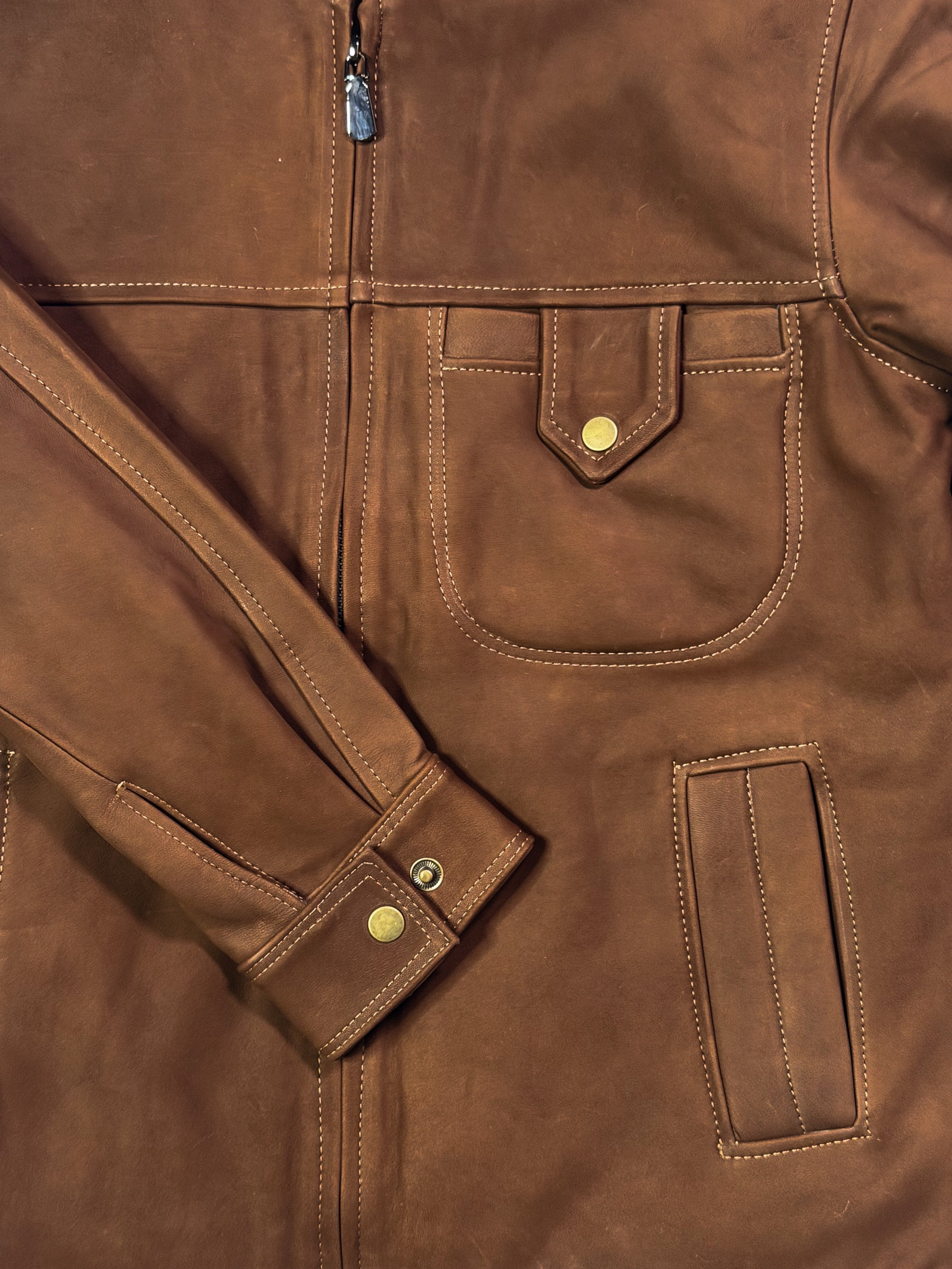 Close-up of a brown leather jacket with visible stitching and buttons.