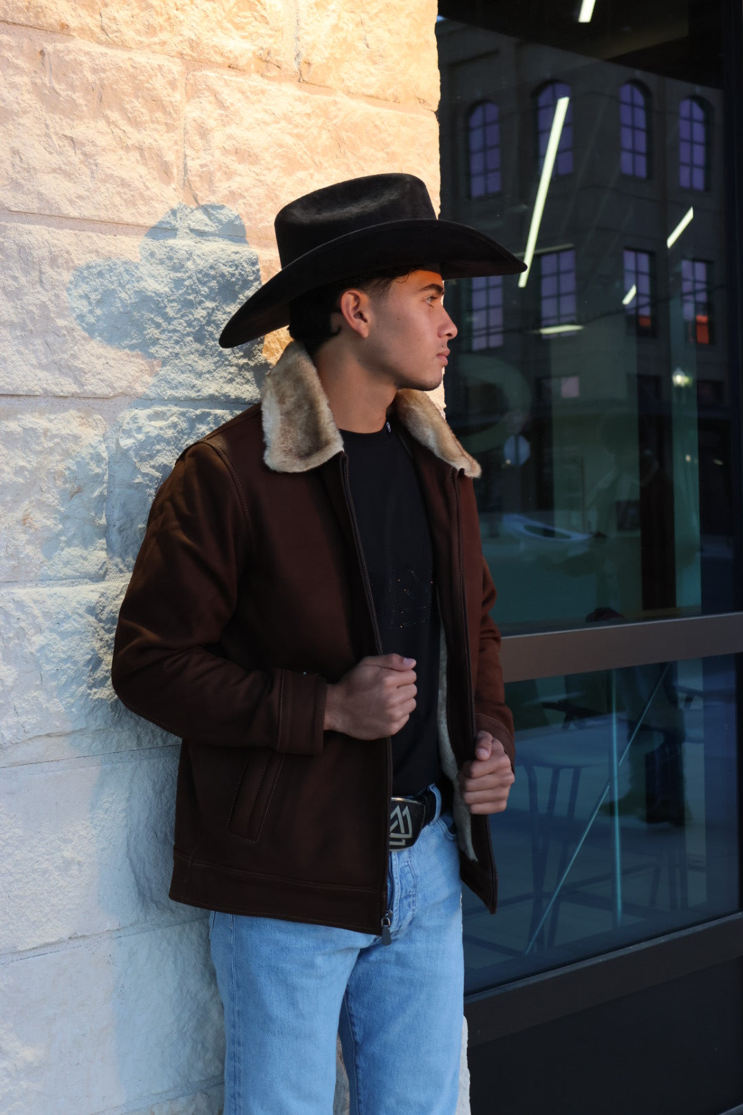 Person wearing a brown jacket with fur collar and black hat 