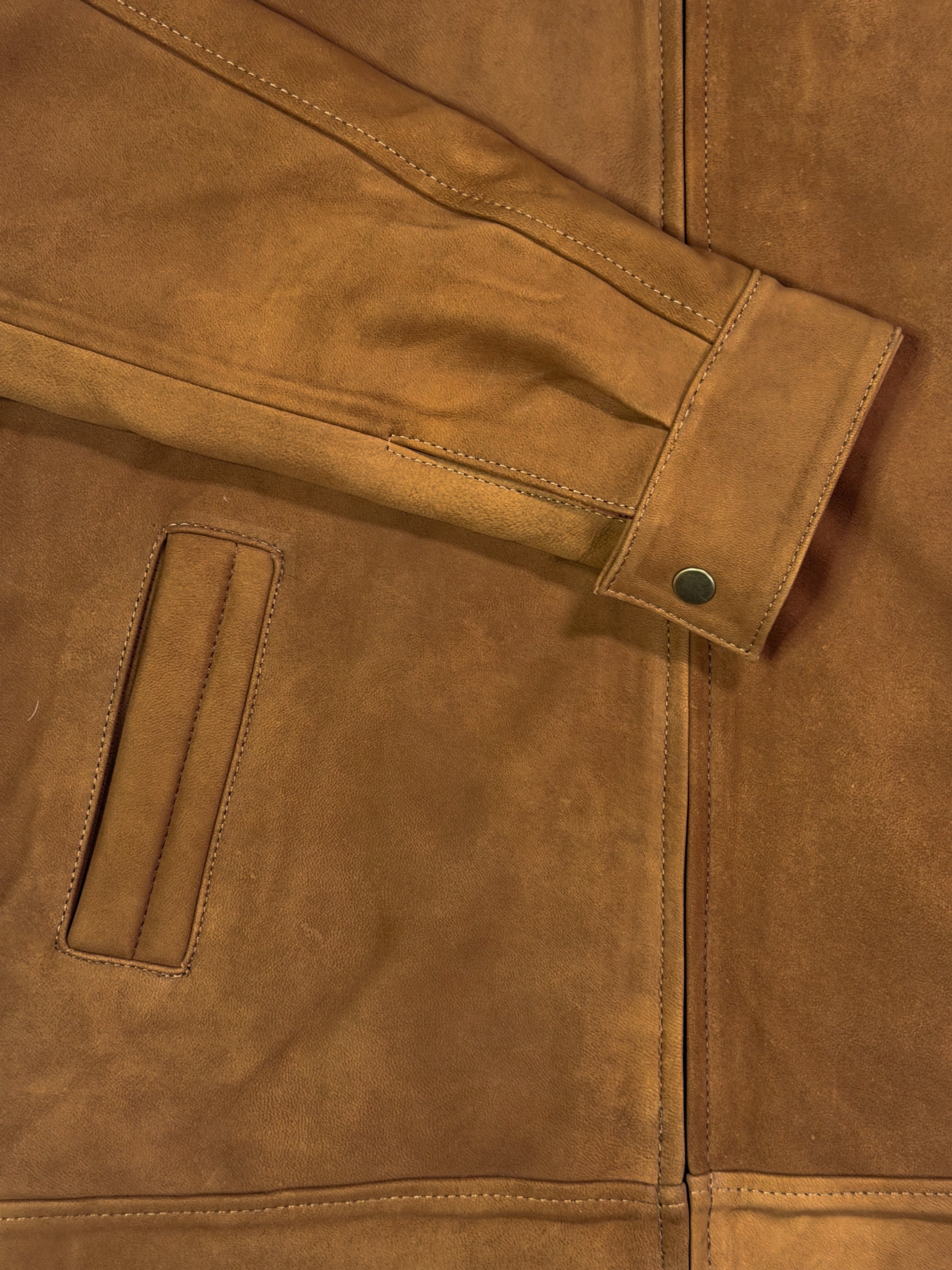 Close-up of a golden leather jacket with a buttoned cuff.