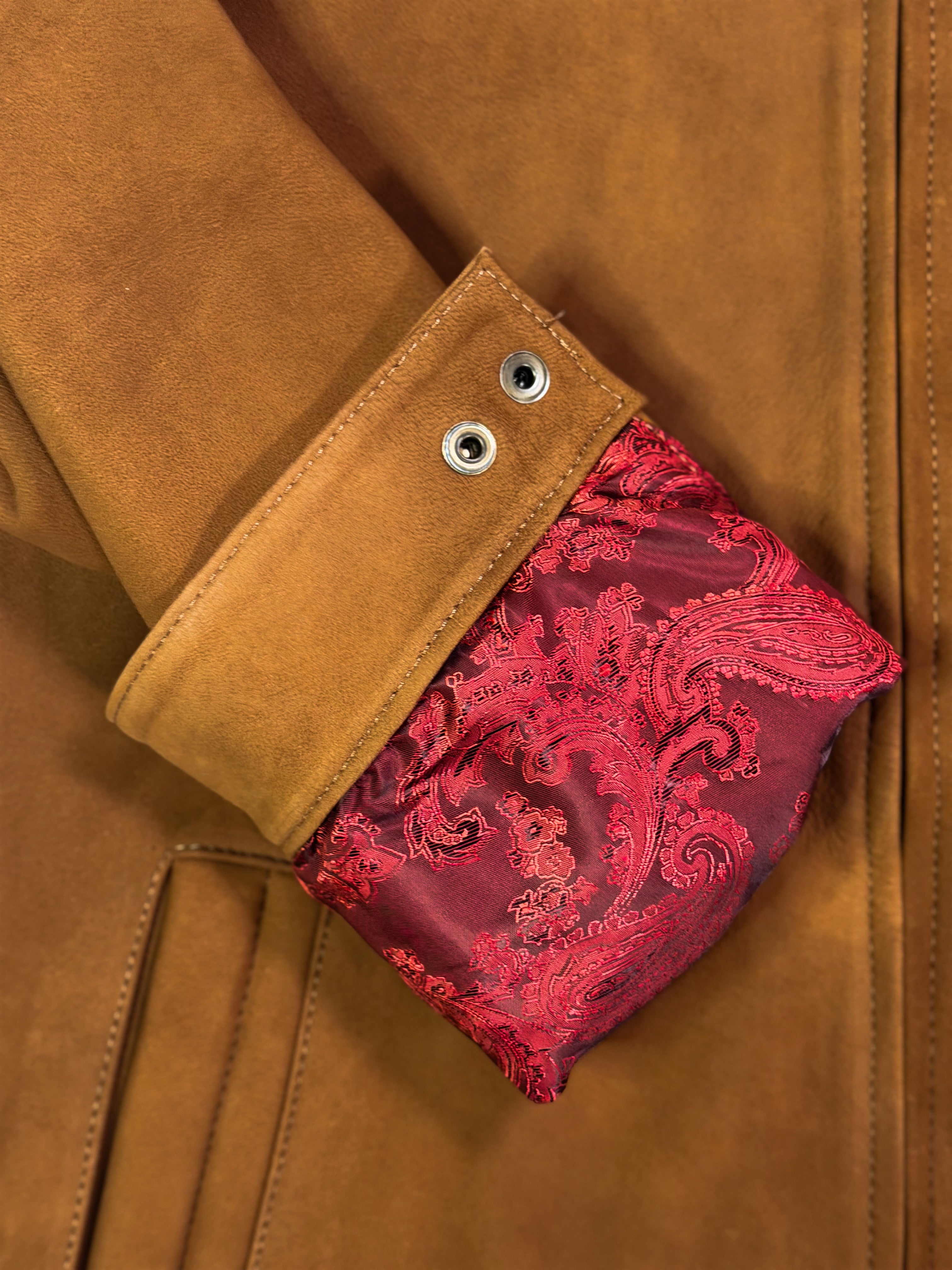 Close-up of a golden leather jacket with a red patterned inner sleeve.