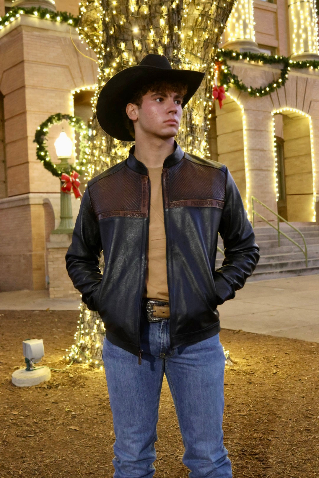 Person wearing a black leather jacket and cowboy hat 