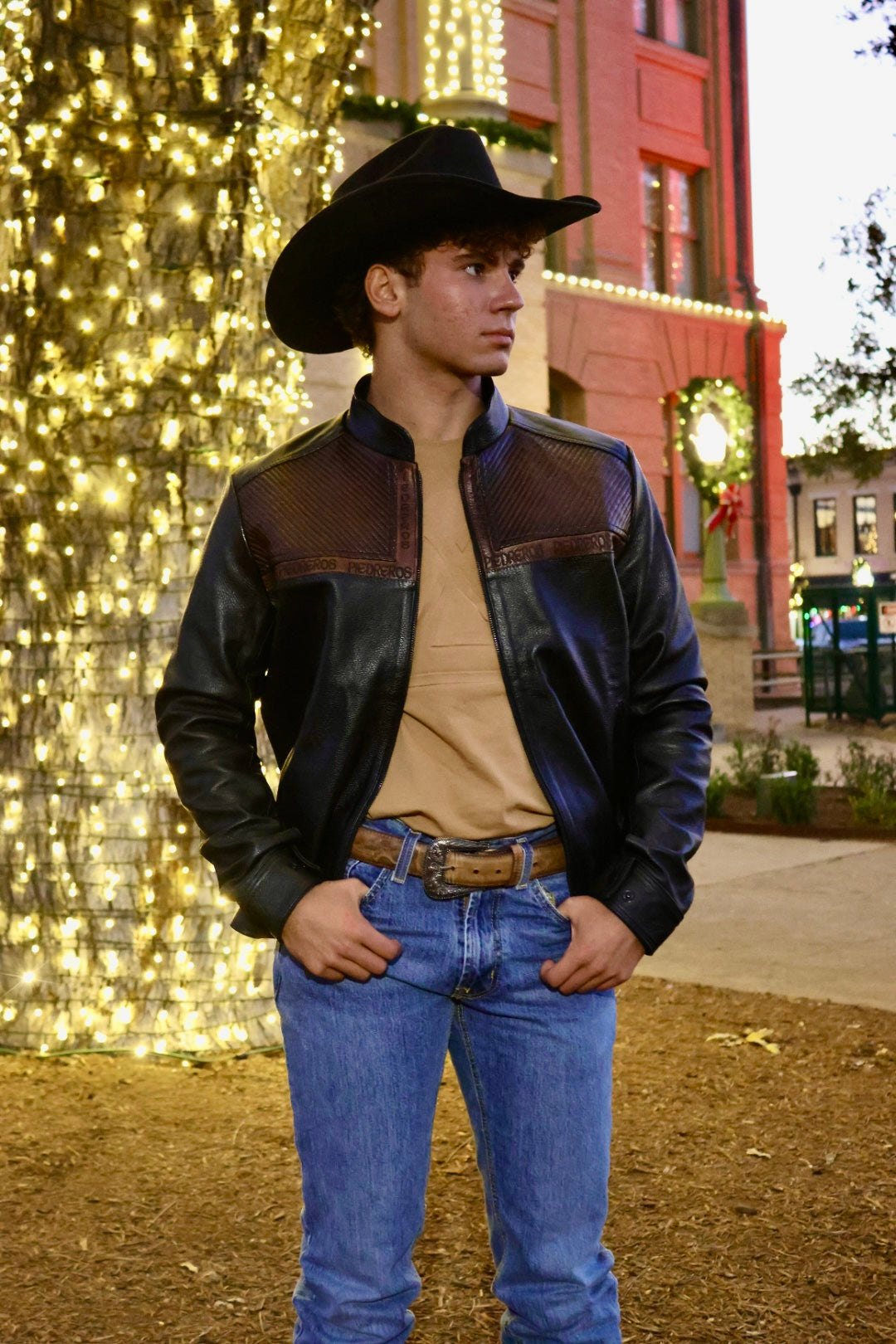Person wearing a black leather jacket and cowboy hat 