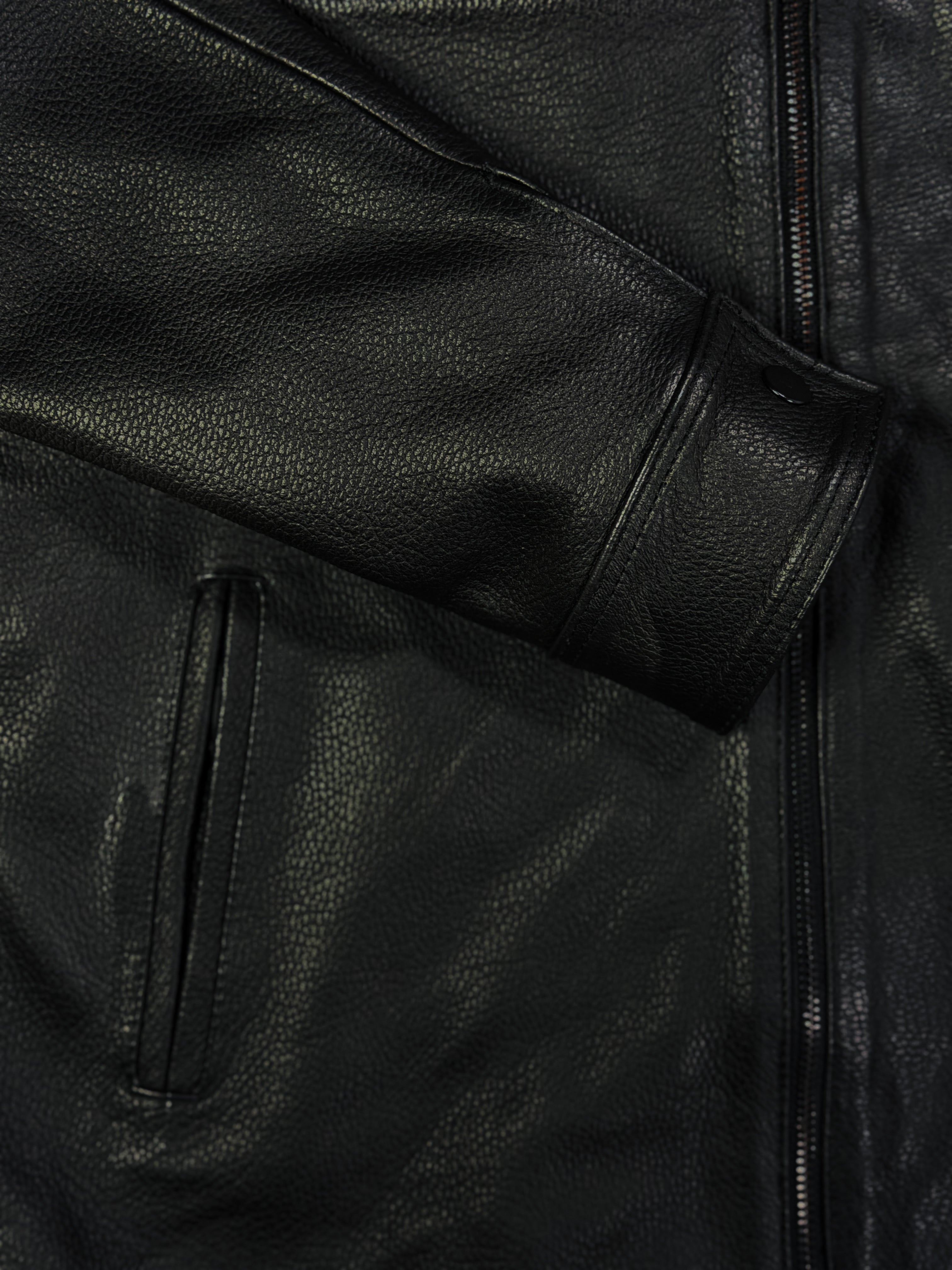 Close-up of a black leather jacket with a focus on texture and stitching and button sleeve