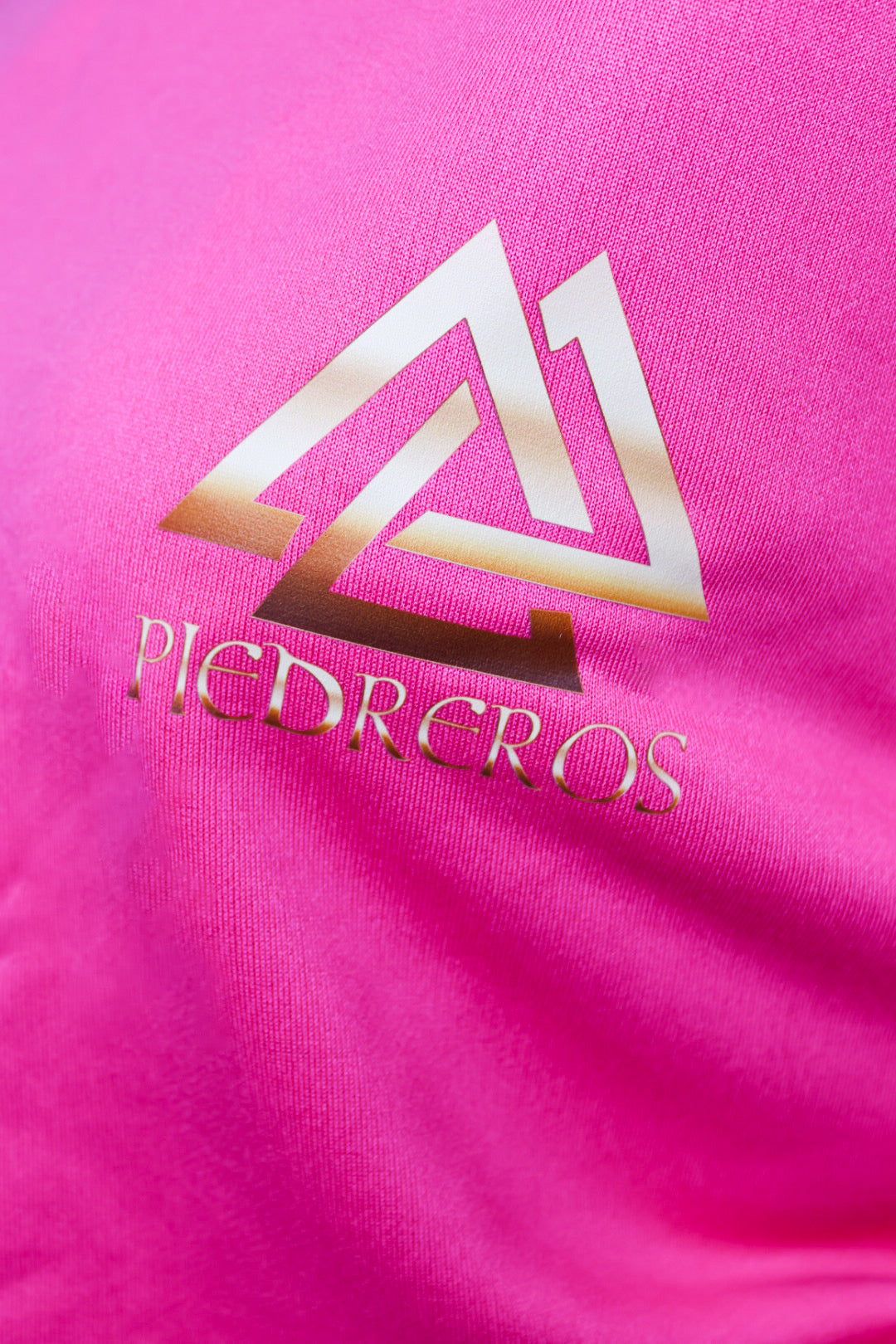 Close up of piedreros logo on pink sweater