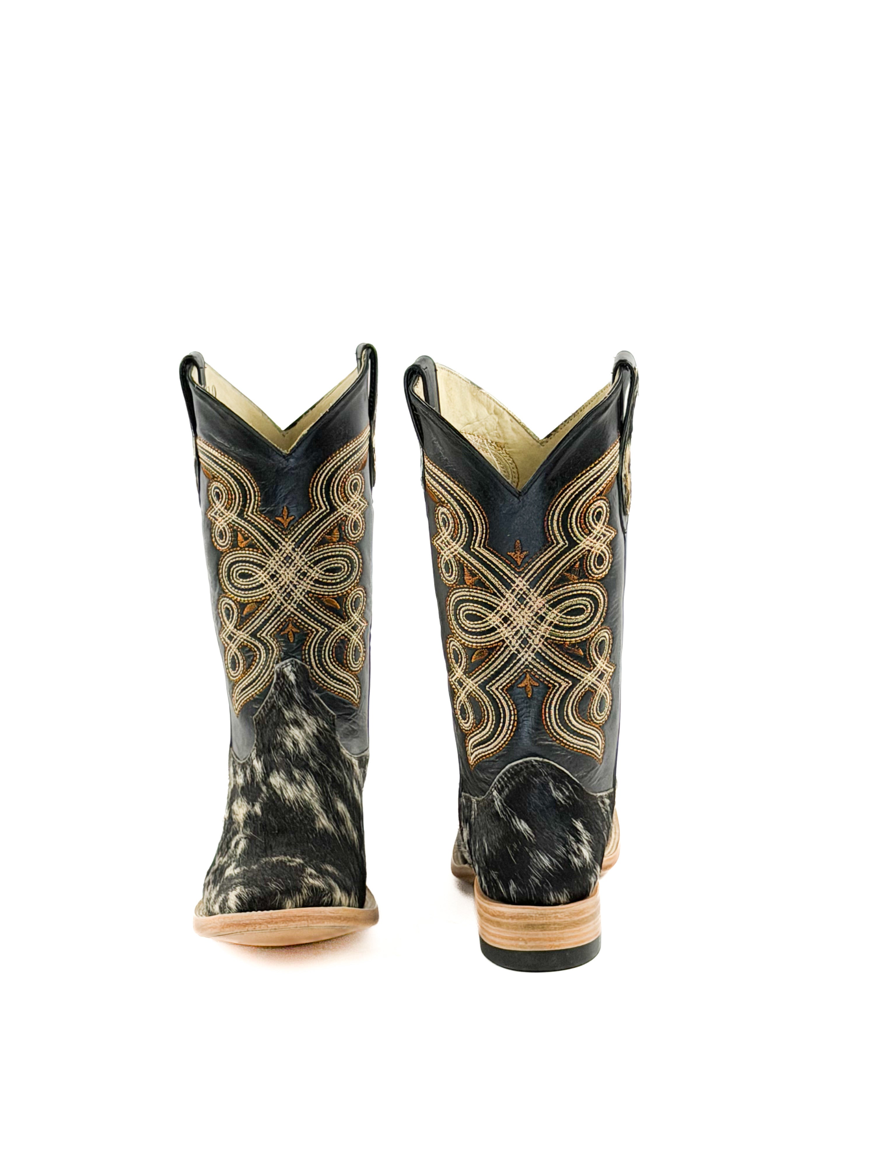 Pair of black and white cowhide square toe boots with intricate designs a black shaft