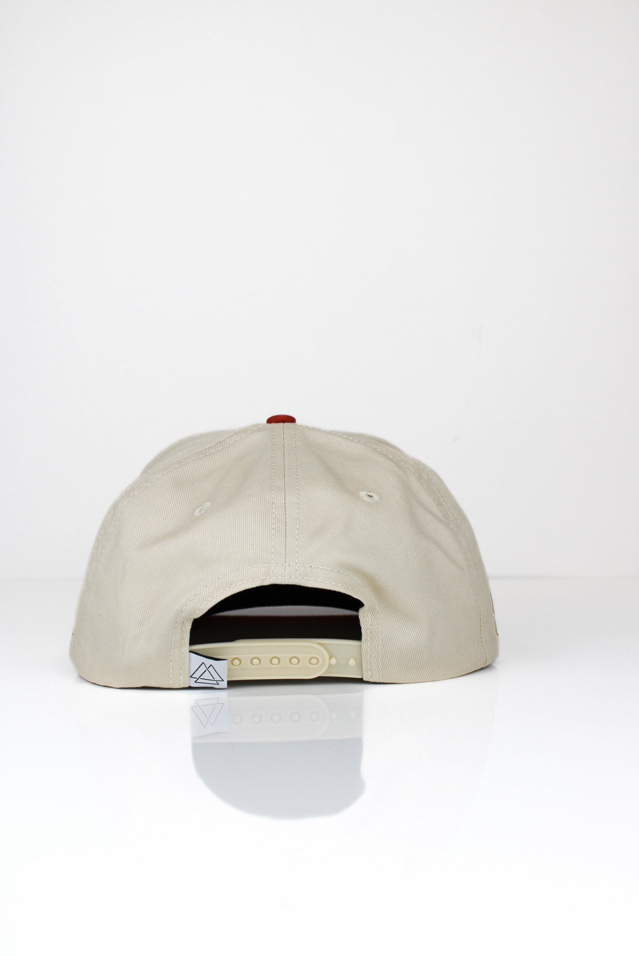 The back of a beige and red baseball cap with adjustable strap