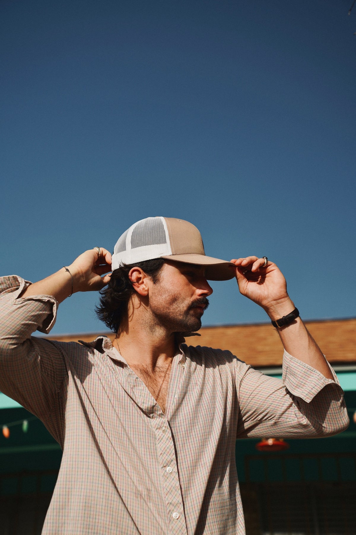 Trey con gorra trucker beige, cielo azul