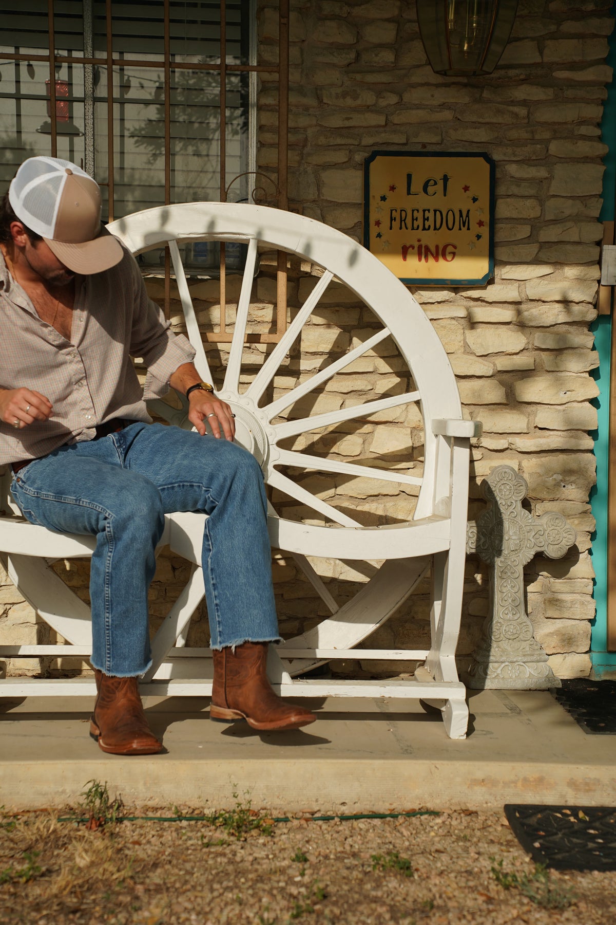 Trey sitting on a wagon wheel bench in The Pecos boots
